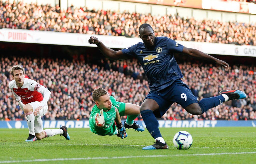Arsenal's German goalkeeper Bernd Leno (C) manages to block and save the shot from Manchester United's Belgian forward Romelu Lukaku (R) during the English Premier League football match between Arsenal and Manchester United at the Emirates Stadium in London on March 10, 2019. (Photo by Ian KINGTON / IKIMAGES / AFP) / RESTRICTED TO EDITORIAL USE. No use with unauthorized audio, video, data, fixture lists, club/league logos or 'live' services. Online in-match use limited to 45 images, no video emulation. No use in betting, games or single club/league/player publications.